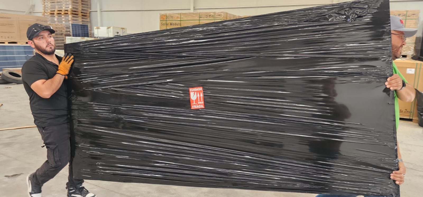 Equipo de PaqueteGo cargando un panel solar marcado como frágil